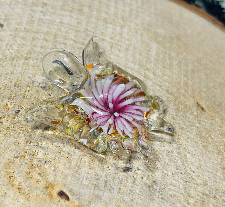 Pendentif en verre en forme de papillon avec fleur à l’intérieur. - Les bijoux de Théa