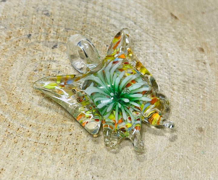 Pendentif en verre en forme de papillon avec fleur à l’intérieur. - Les bijoux de Théa