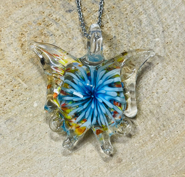 Pendentif en verre en forme de papillon avec fleur à l’intérieur. - Les bijoux de Théa