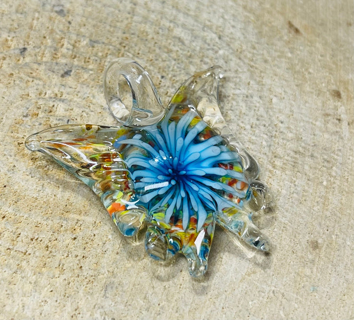 Pendentif en verre en forme de papillon avec fleur à l’intérieur. - Les bijoux de Théa