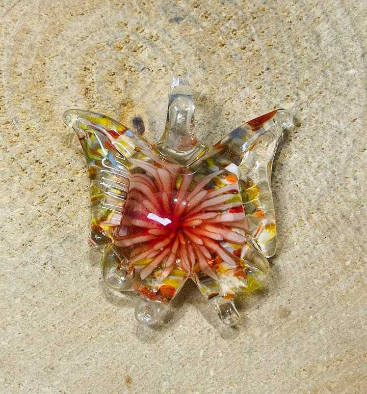 Pendentif en verre en forme de papillon avec fleur à l’intérieur. - Les bijoux de Théa