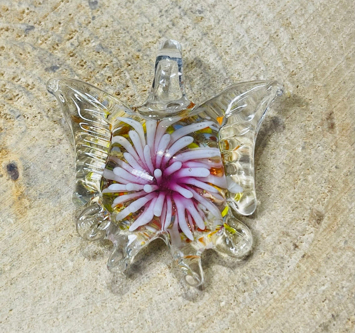 Pendentif en verre en forme de papillon avec fleur à l’intérieur. - Les bijoux de Théa