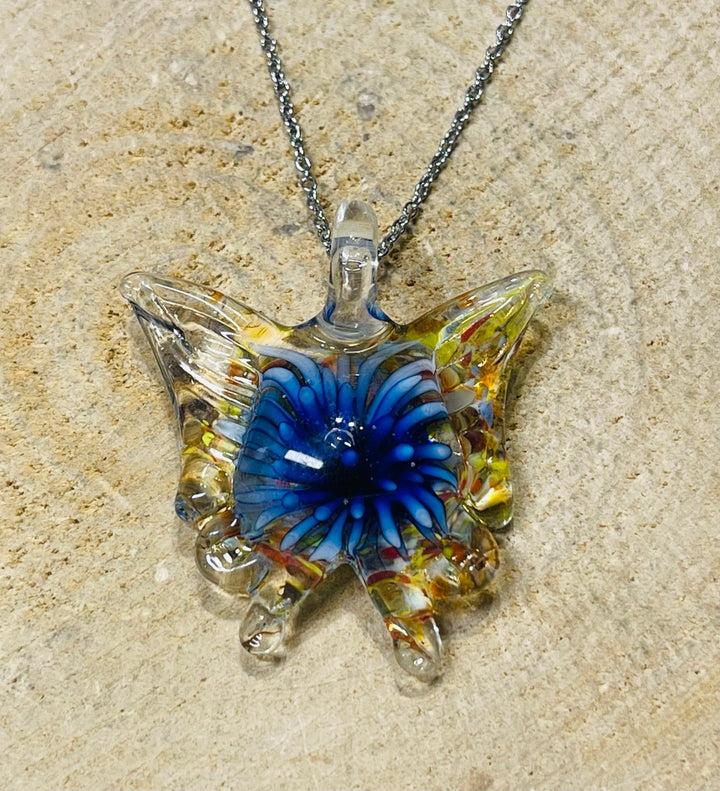 Pendentif en verre en forme de papillon avec fleur à l’intérieur. - Les bijoux de Théa