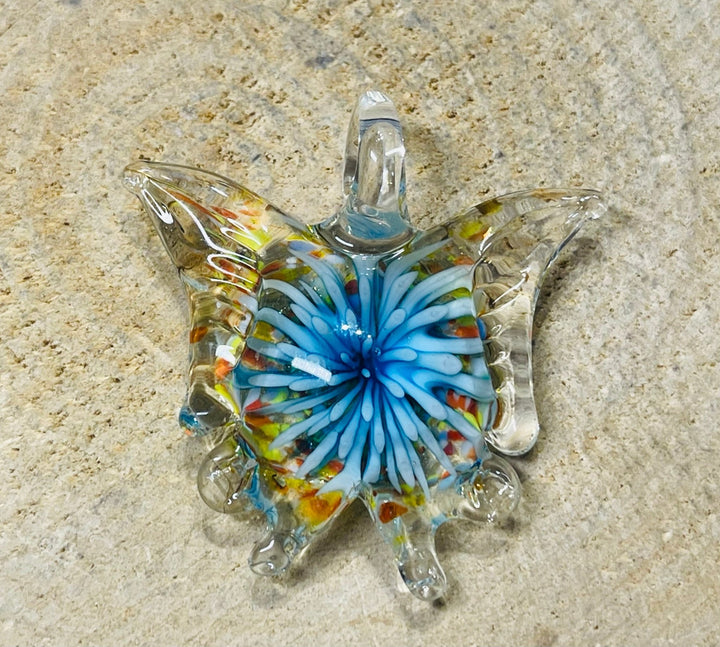 Pendentif en verre en forme de papillon avec fleur à l’intérieur. - Les bijoux de Théa