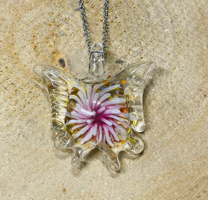 Pendentif en verre en forme de papillon avec fleur à l’intérieur. - Les bijoux de Théa